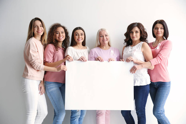 Группа женщин с шелковыми лентами на диване возле светлой стены. Концепция информированности о раке груди
 - Фото, изображение