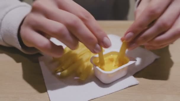 Woman is eating French fries with cheese sauce in cafe. Close-up hands. - Video, Çekim
