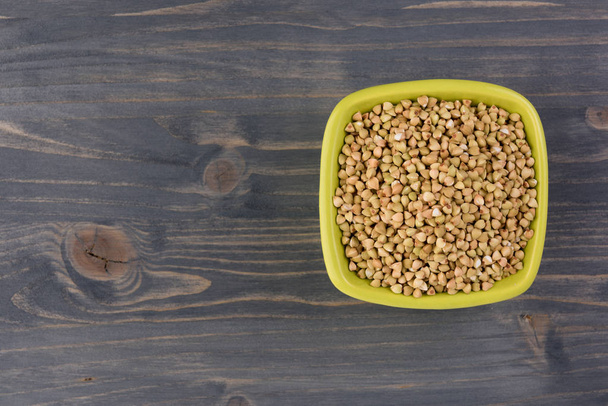 Natural fresh green buckwheat in ceramic bowl on wooden background. Top view - 写真・画像