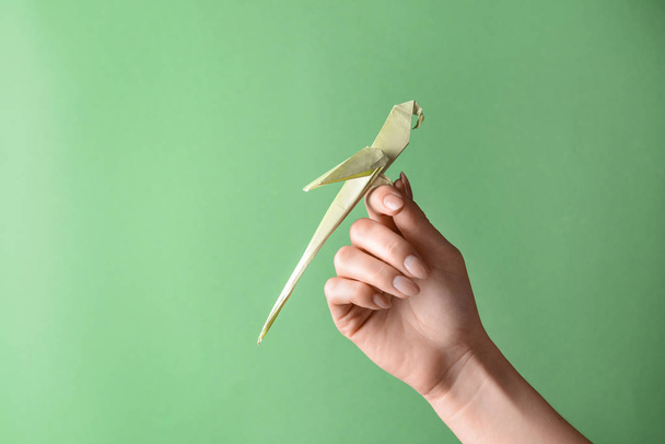 Main féminine avec origami perroquet sur fond de couleur
 - Photo, image