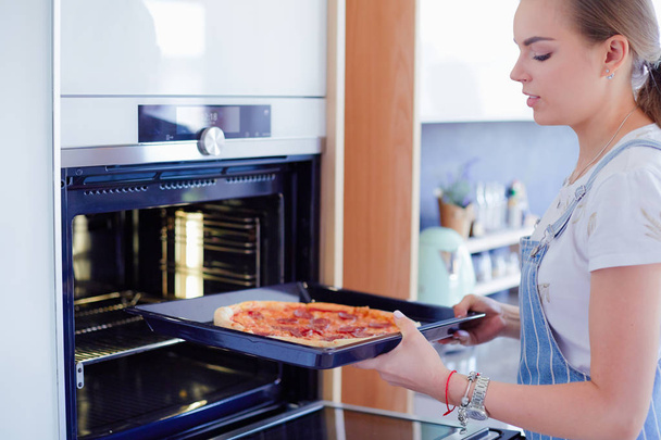 Happy young woman cooking pizza at home - Foto, immagini