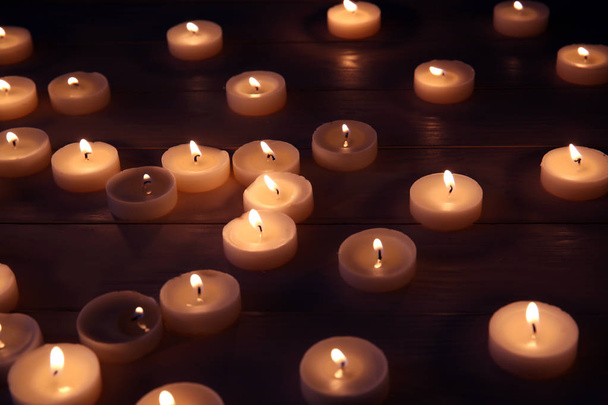 viele brennende Kerzen auf dem Tisch in der Dunkelheit - Foto, Bild