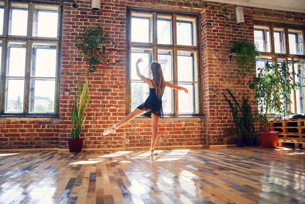 Young ballerina in black tutu practicing dance moves. Young girl in ballet dress at dance school. - Foto, Imagen