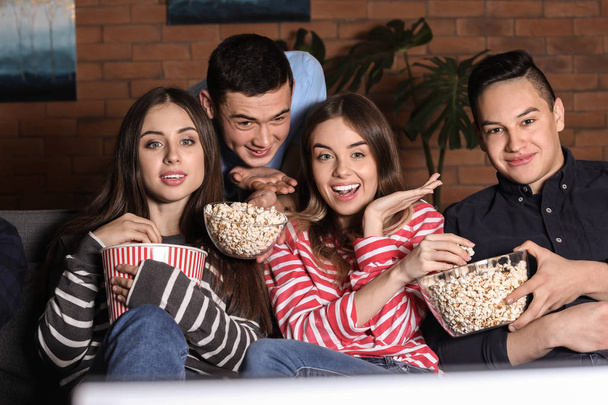 Friends watching TV and eating popcorn at home - Фото, изображение