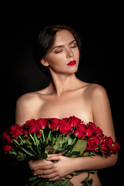 beautiful young woman with a large bouquet of red roses - Foto, Imagen