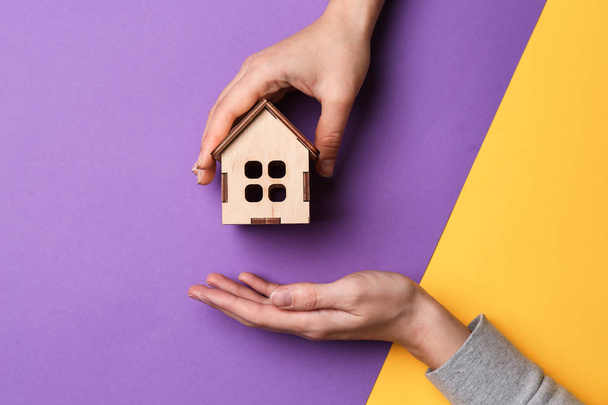 Female hands with figure of house on color background. Mortgage concept - Zdjęcie, obraz