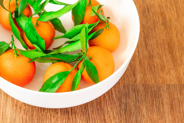 frisch gepflückte Mandarinen auf einem braunen Holztisch - Foto, Bild