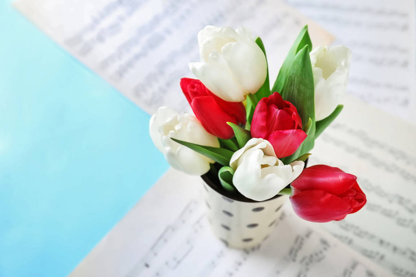 Tazza con mazzo di bei fiori e fogli di note sul tavolo
 - Foto, immagini