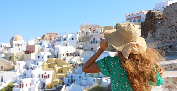 Oia, Santorini Adası Yunanistan Turizm Seyahat kız. Europe seyahat şapkasını tutarak ve panoramik manzarayı kadın yaz. - Fotoğraf, Görsel