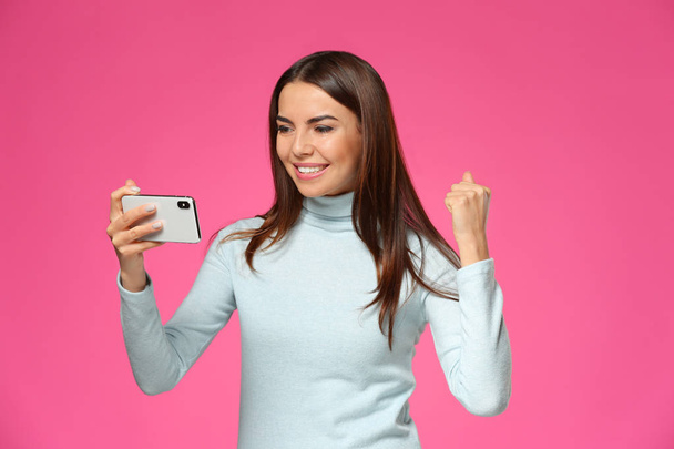 感情的な若い女性の背景の色にモバイル ゲームをプレイ - 写真・画像