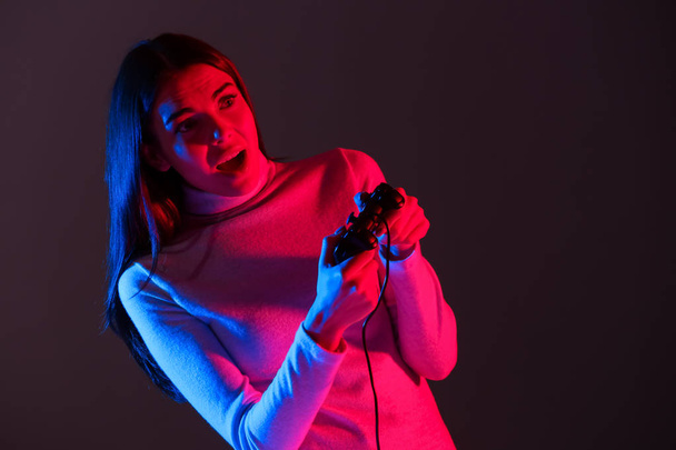 暗闇の中でコンピューター ゲームをプレイして感情的な若い女性 - 写真・画像