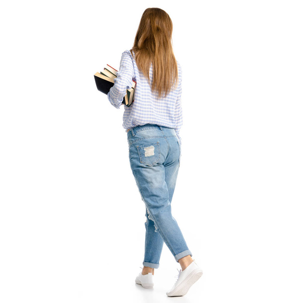 Woman in blue jeans and shirt with books in hands goes - Foto, Bild
