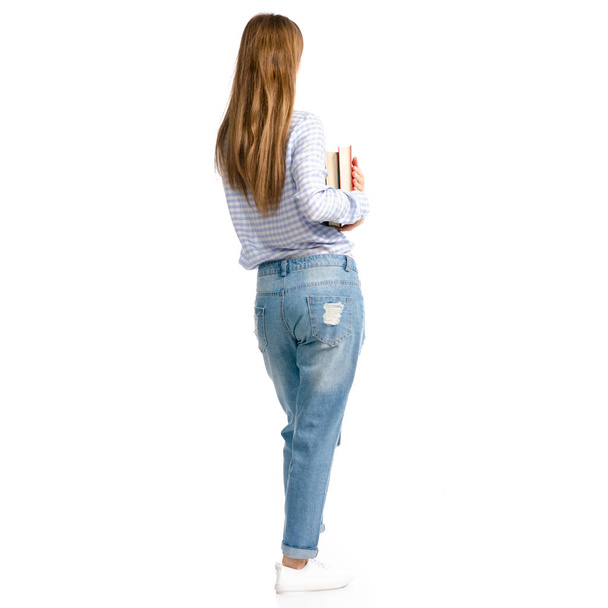 Woman in blue jeans and shirt with books in hands goes - Foto, imagen