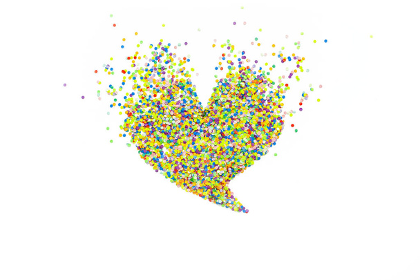 Heart made of colored confetti. Small circles of colored paper. White background. View from above. Colored heart. - Photo, Image