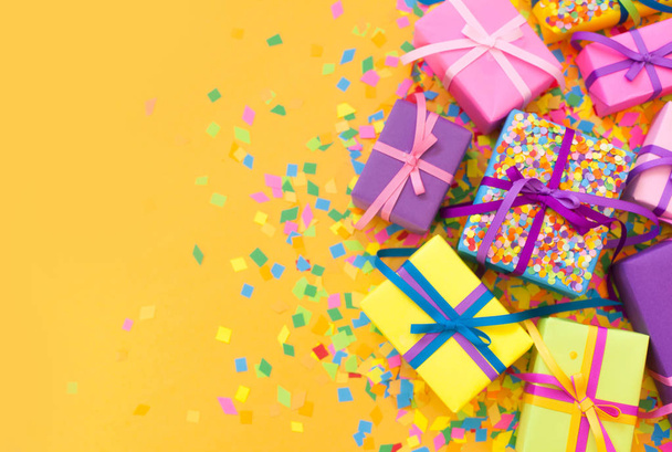 Colored gift boxes with colorful ribbons. Yellow background. Gifts for Christmas or a birthday. - Photo, Image