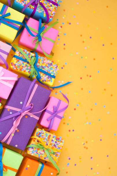 Colored gift boxes with colorful ribbons. Yellow background. Gifts for Christmas or a birthday. - Фото, зображення