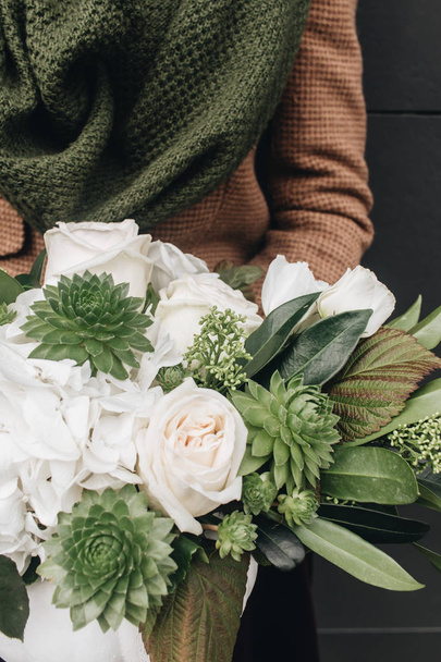 Frau hält schönen Strauß mit weißen Blumen und exotischen grünen Pflanzen  - Foto, Bild