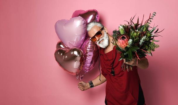 bearded middle-aged man with balloons and flowers. - Valokuva, kuva