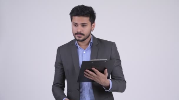 Young bearded Indian businessman directing while holding clipboard - Séquence, vidéo