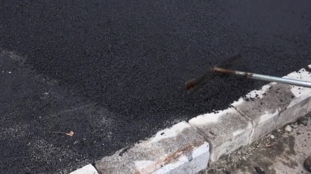 Une équipe de travailleurs a mis l'asphalte chaud sur une rue Travailleurs de la construction routière avec des pelles en uniformes de protection. Travailler dans la journée chaude
. - Séquence, vidéo