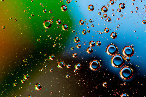 Macro shot of backlit liquid with small bubbles in it over colored background. - Zdjęcie, obraz