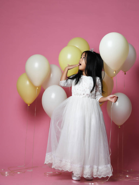 surprised kid girl with balloons in princess dress with tiara looks up - Фото, изображение