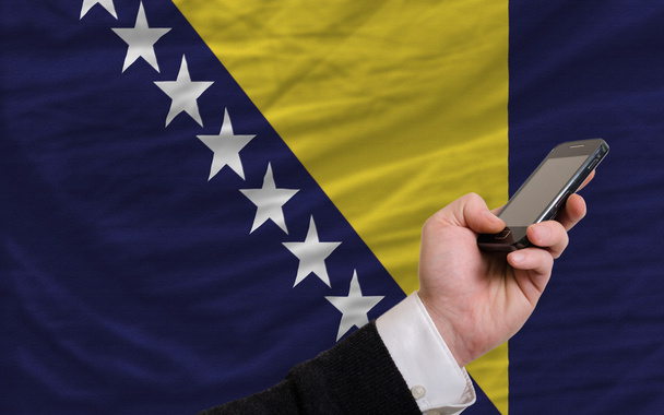 teléfono celular frente a la bandera nacional de bosnia herzegovina
 - Foto, imagen