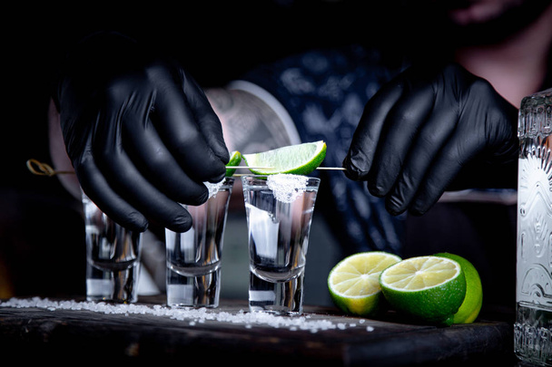 aperitivo con amigos en el bar, tres vasos de alcohol con lima y sal para decorar. Tequila shots, enfoque selectivo
 - Foto, imagen