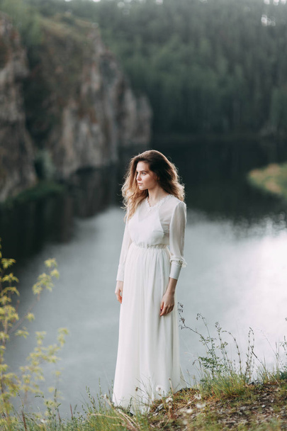 Boudoir morning bride in nature in a white dress. Wedding series on cliffs and river bends. - Foto, afbeelding