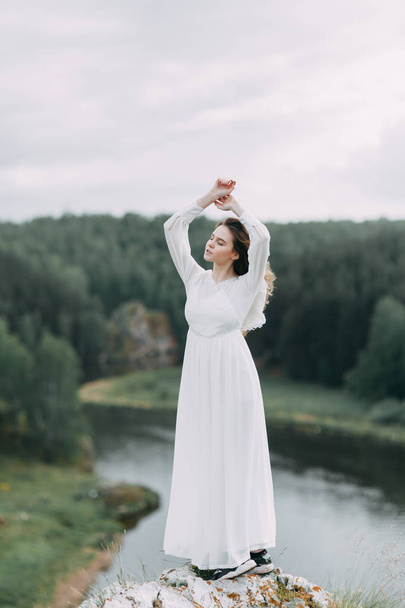 Boudoir morning bride in nature in a white dress. Wedding series on cliffs and river bends. - Фото, изображение