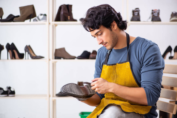 Молодий чоловік ремонтує взуття в майстерні
  - Фото, зображення