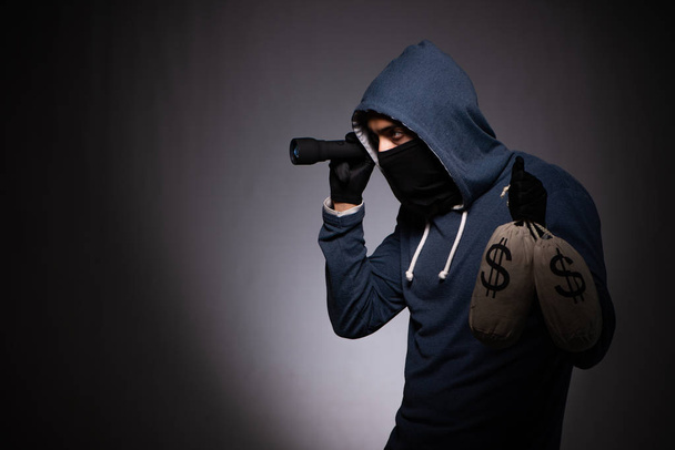 junger Gangster mit Kapuze auf grauem Hintergrund  - Foto, Bild