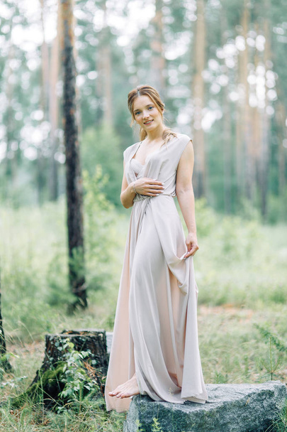 Boudoir photo shoot of the bride in the woods with a bouquet. Flying dress and beautiful girl in the Park. - Valokuva, kuva