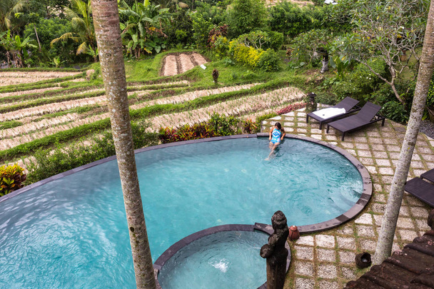 Chica en piscina infinita hacia la selva con palmeras
. - Foto, Imagen