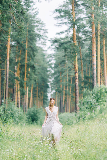 Boudoir photo shoot of the bride in the woods with a bouquet. Flying dress and beautiful girl in the Park. - Fotó, kép