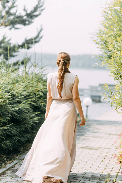 Boudoir fotoshoot van de bruid in het park met een boeket. Een vliegende jurk en een mooi meisje aan het meer. - Foto, afbeelding