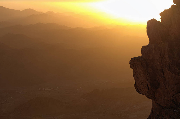 El sol sale detrás de la roca. Misterioso paisaje del Monte Sinaí (Monte Horeb, Gabal Musa, Moisés Monte) durante la salida del sol. Península del Sinaí de Egipto. Lugar de peregrinación y famoso destino turístico
. - Foto, Imagen