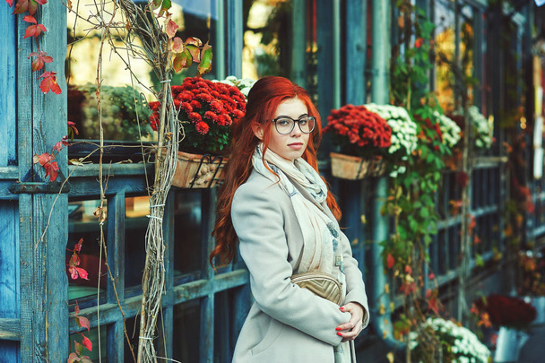 Fiatal vörös hajú nő a városban. Lány visel kabátot - Fotó, kép