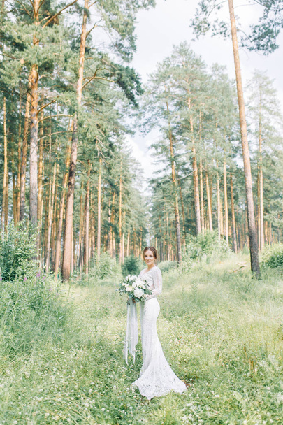The bride in a wedding dress in nature with a bouquet. Boudoir photo shoot in pine lemu in the style of fine art. - Fotografie, Obrázek