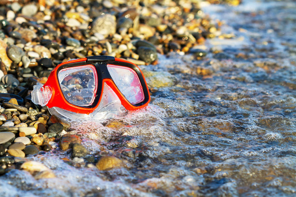 Masque rouge pour plonger sur la plage de galets
 - Photo, image