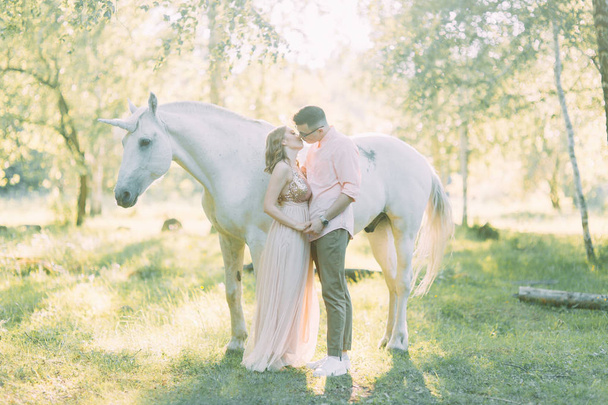Fabulous photo shoot of a couple with a unicorn. Air series in the sunset in the forest with a horse. - Foto, afbeelding