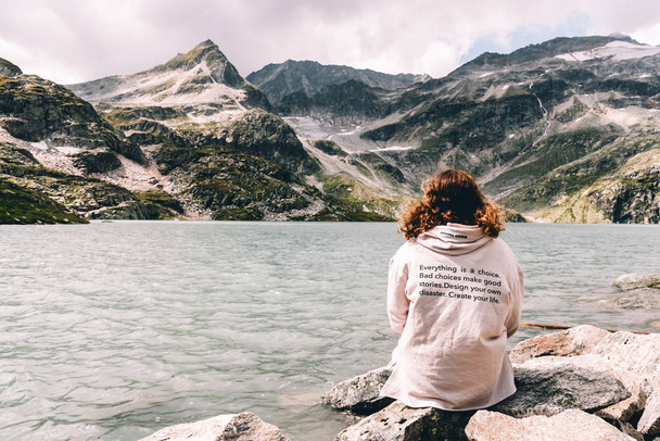 Jeune femme assise au bord d'un lac de montagne dans les Alpes
 - Photo, image