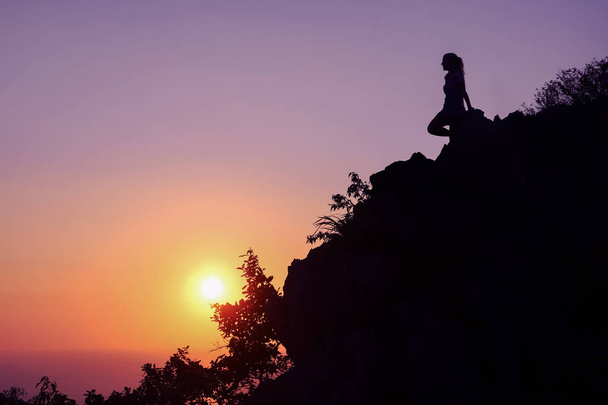 Gelukkige vrouw genieten op de top van de berg bij zonsondergang. Silhouet hemelachtergrond. - Foto, afbeelding