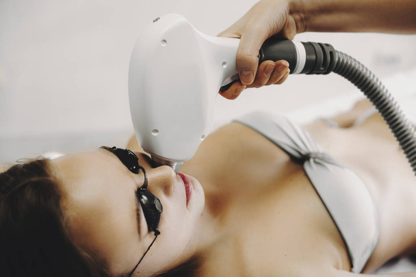 Foto de cerca de una mujer que está haciendo depilación láser en la cara en un salón
. - Foto, imagen