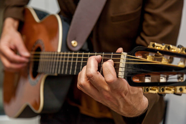 Detailní záběr rukou hudebníka hrajícího na kytaru. Prsty hudebníka mačkají struny na kytaře. Hudebník hrající na baskytaru - Fotografie, Obrázek