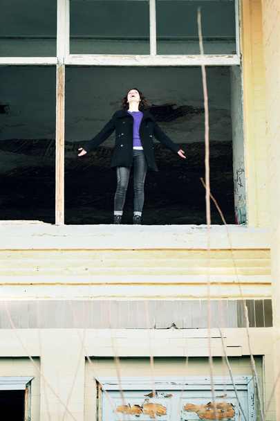 молодая женщина, стоящая в окне заброшенного дома
 - Фото, изображение