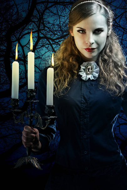 Beautiful witch in a gothic dress with a candlestick - Photo, Image