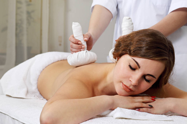 Thai Ball Massage. Woman getting SPA thai herbal compress massage. - Photo, Image