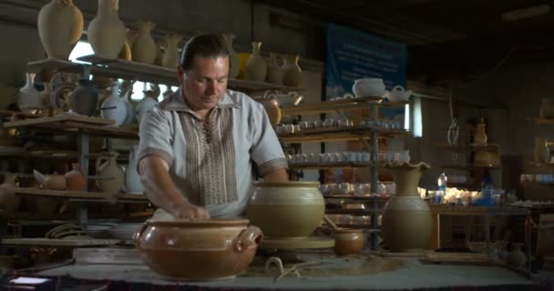 Potter cuts clay jug from spinning wheel with a string then takes it off and puts on a clay plate. - Footage, Video