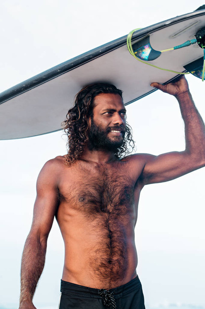Un jeune homme à la peau foncée et à la planche de surf
 - Photo, image